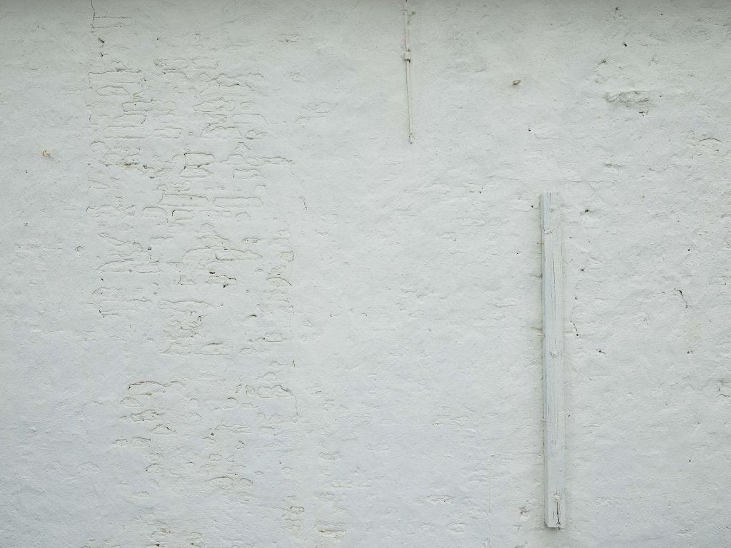 Muur met wit stucwerk en balk