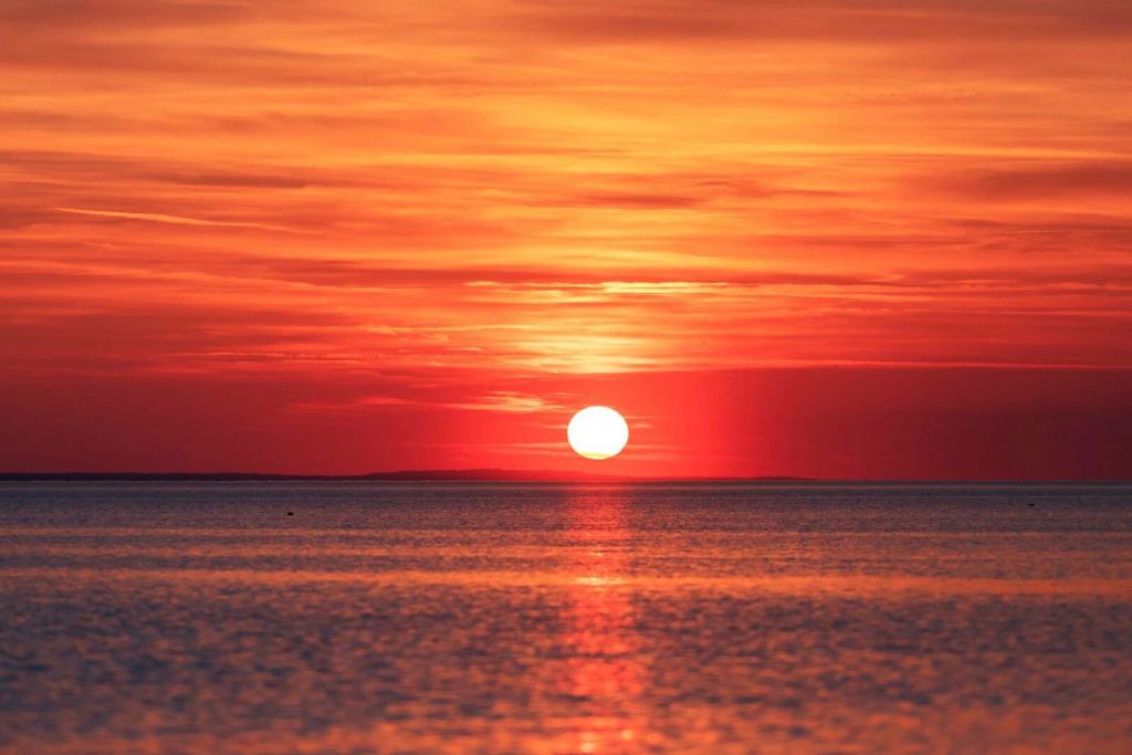 Vuurrode zonsondergang boven kalme zee