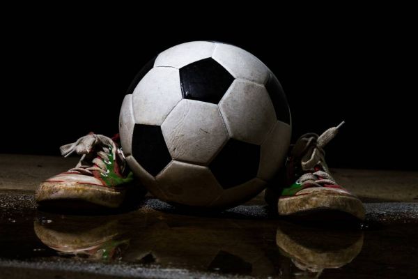 moeilijk India longontsteking Behang met een voetbal tussen twee sneakers - Fotobehang