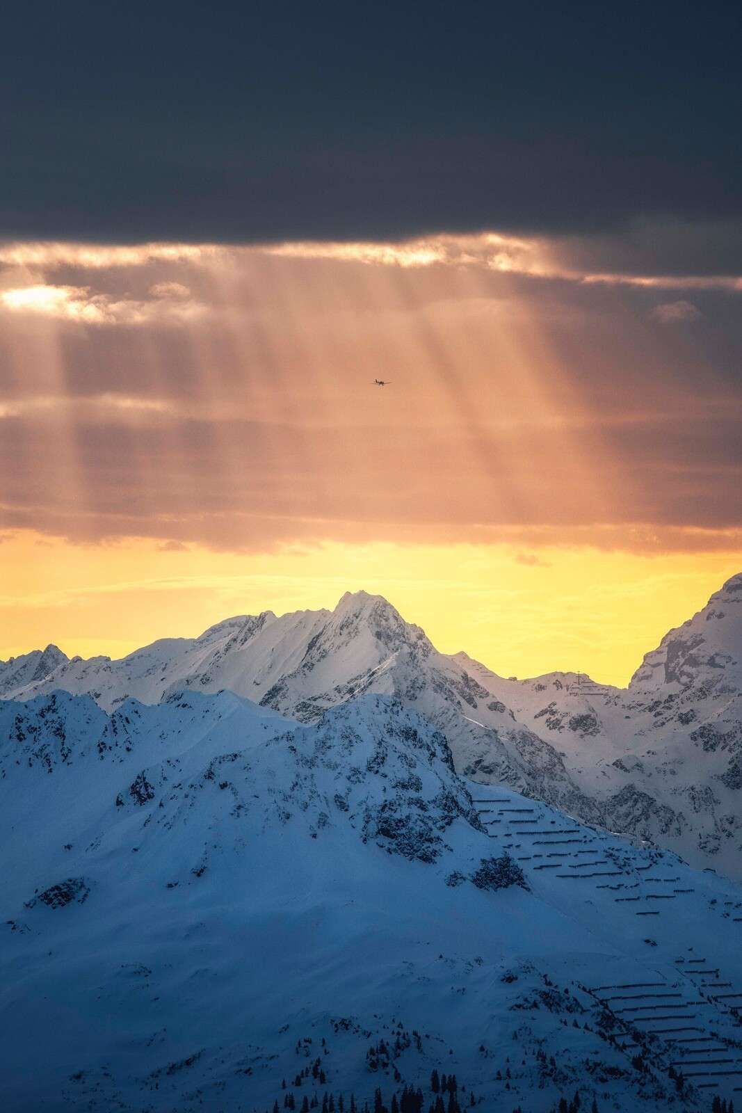 Zonnestralen boven besneeuwde bergtoppen