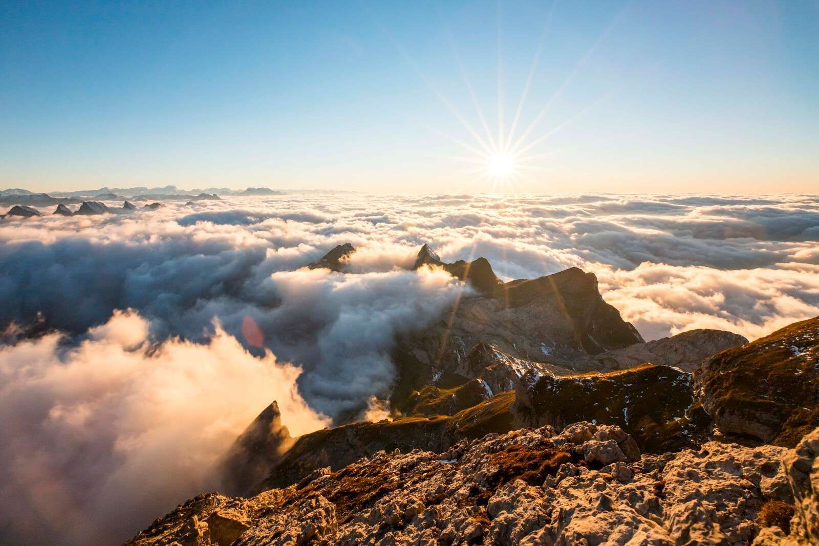 Zon boven wolkendek en bergtoppen
