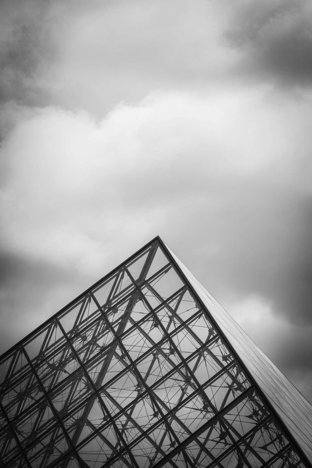 Glazen piramide onder wolkenlucht